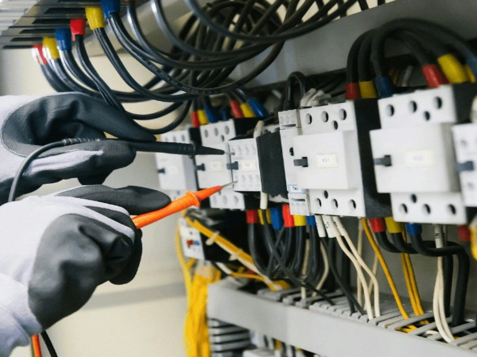 Elektriker misst mit Prüfspitzen an den Klemmen eines Sicherungskastens